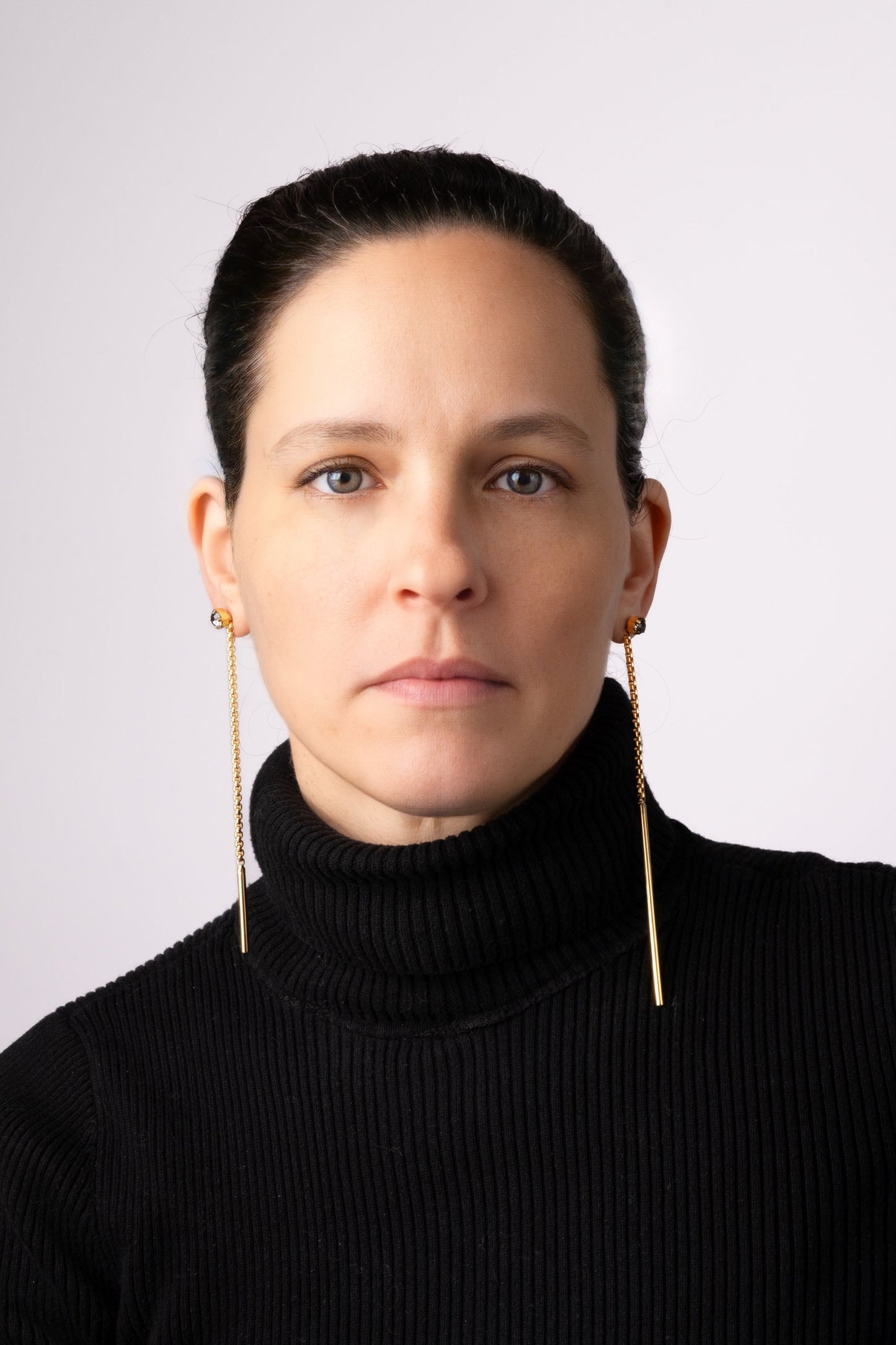 a woman wearing a black sweater and gold earrings