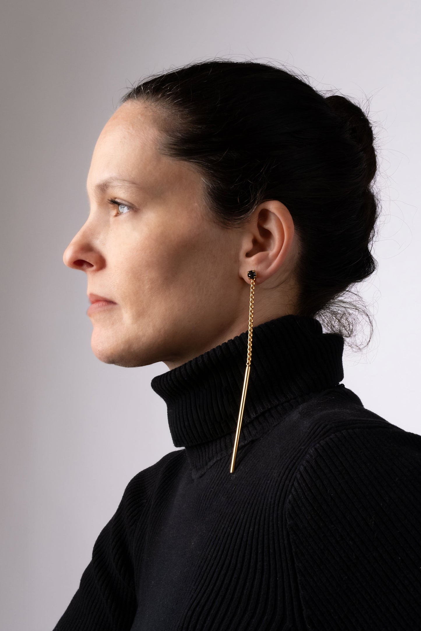 a woman wearing a black turtle neck sweater and gold earrings