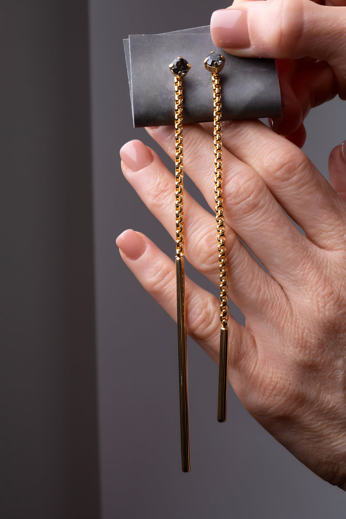 a person holding a pair of gold earrings