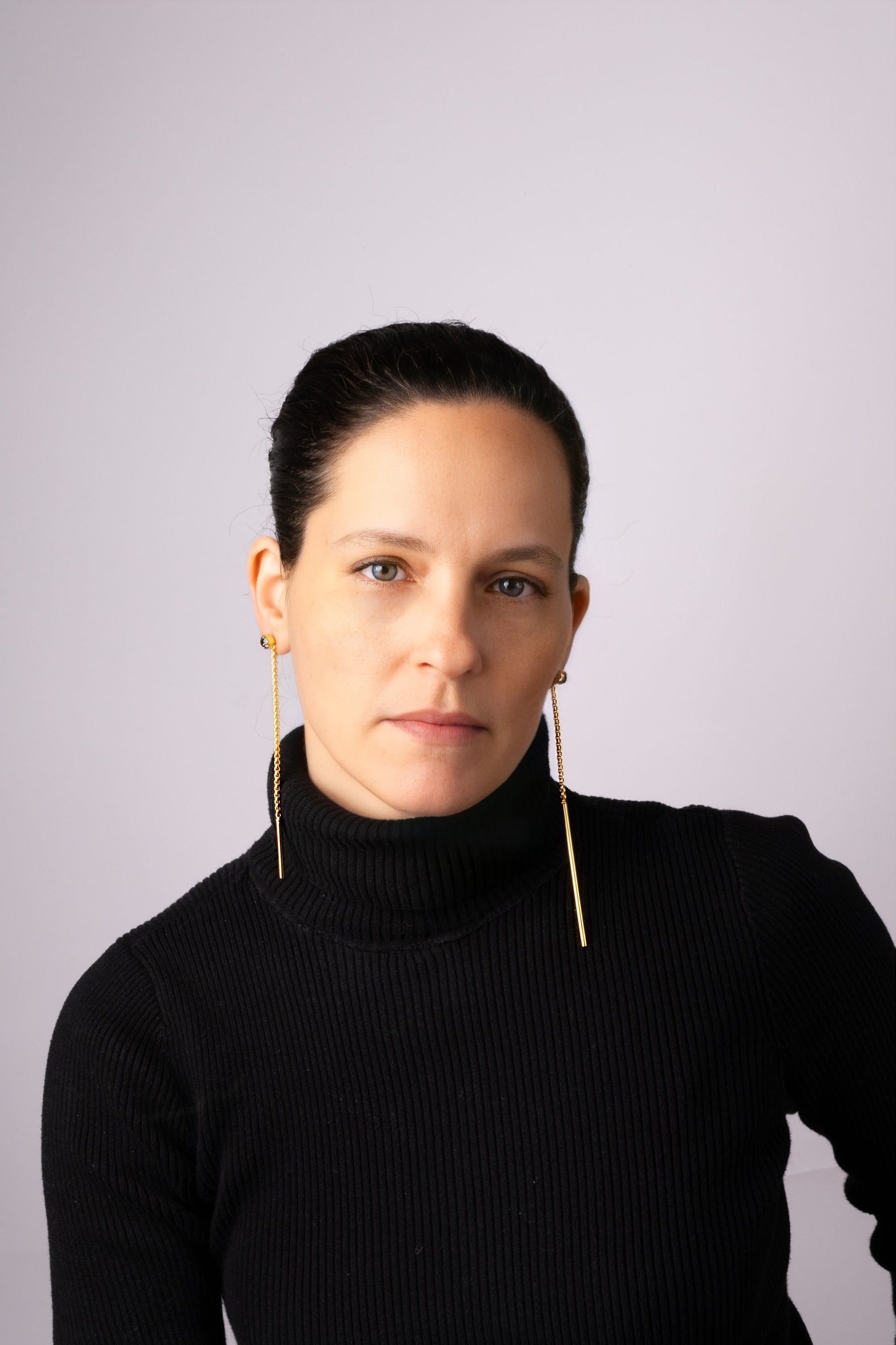a woman wearing a black sweater and gold earrings