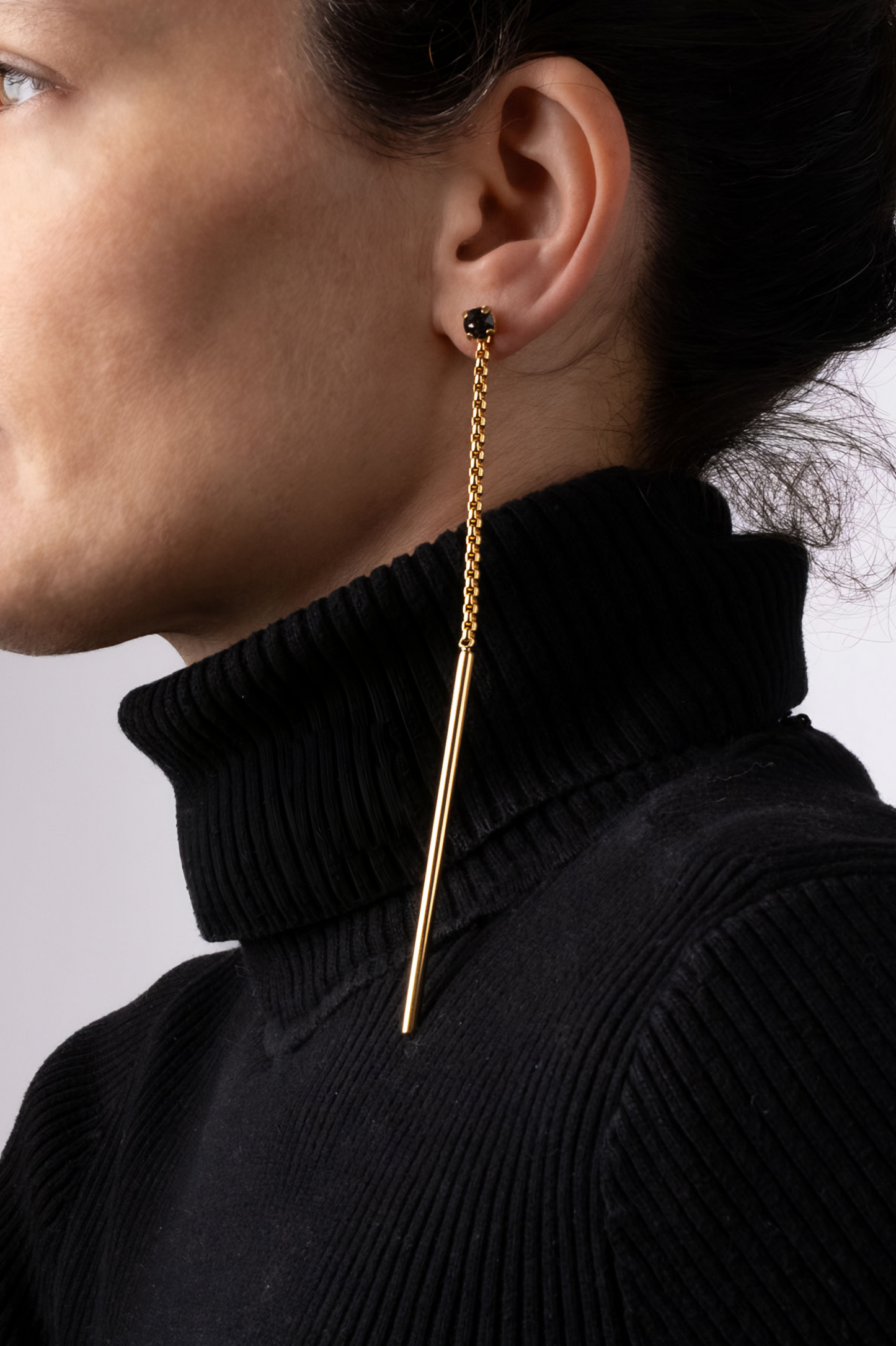 a woman wearing a black turtle neck sweater and gold earrings