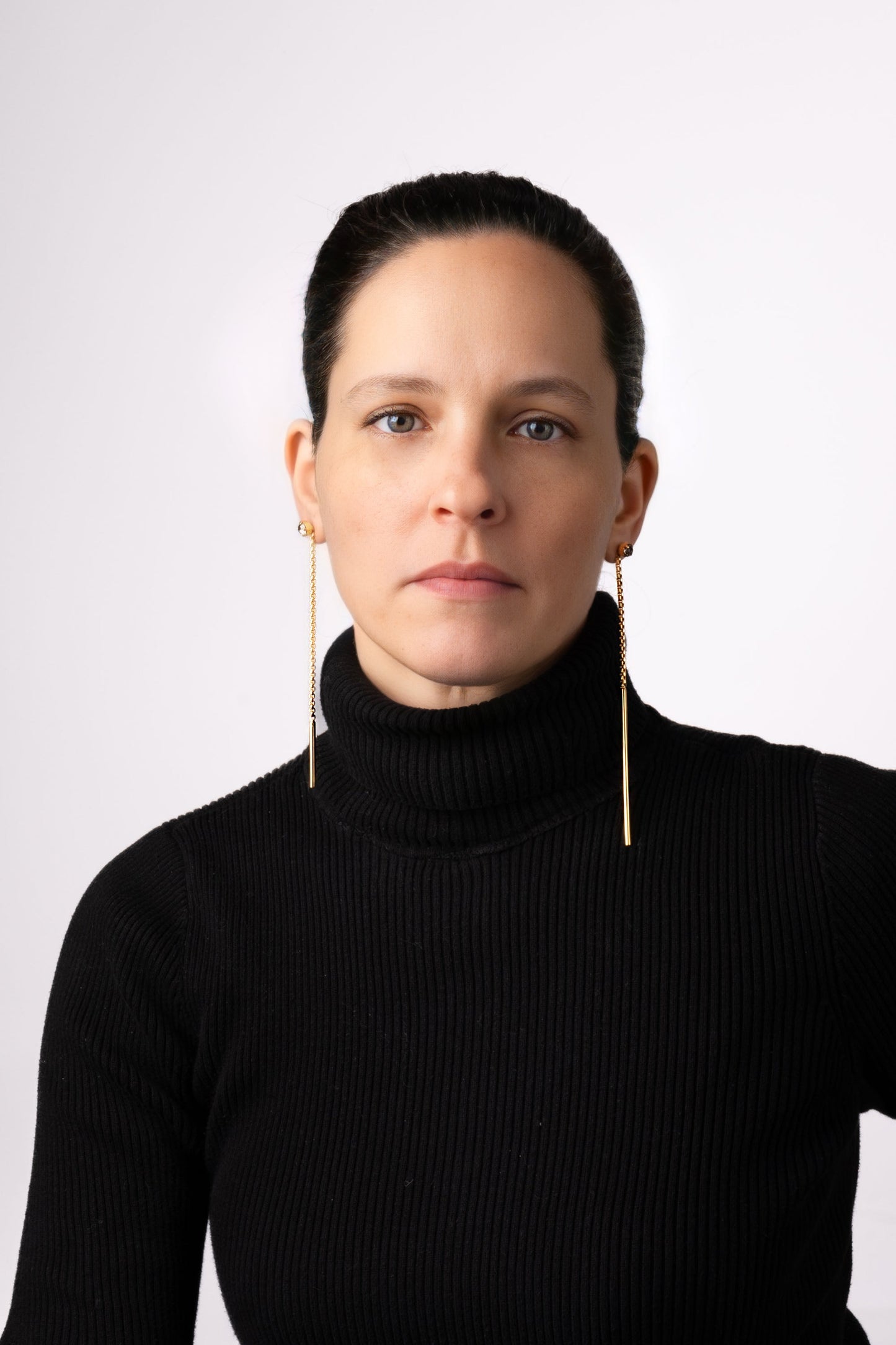 a woman wearing a black sweater and gold earrings