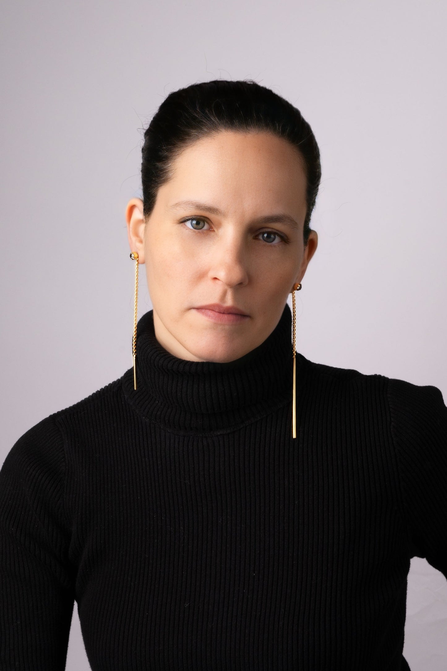 a woman wearing a black sweater and gold earrings