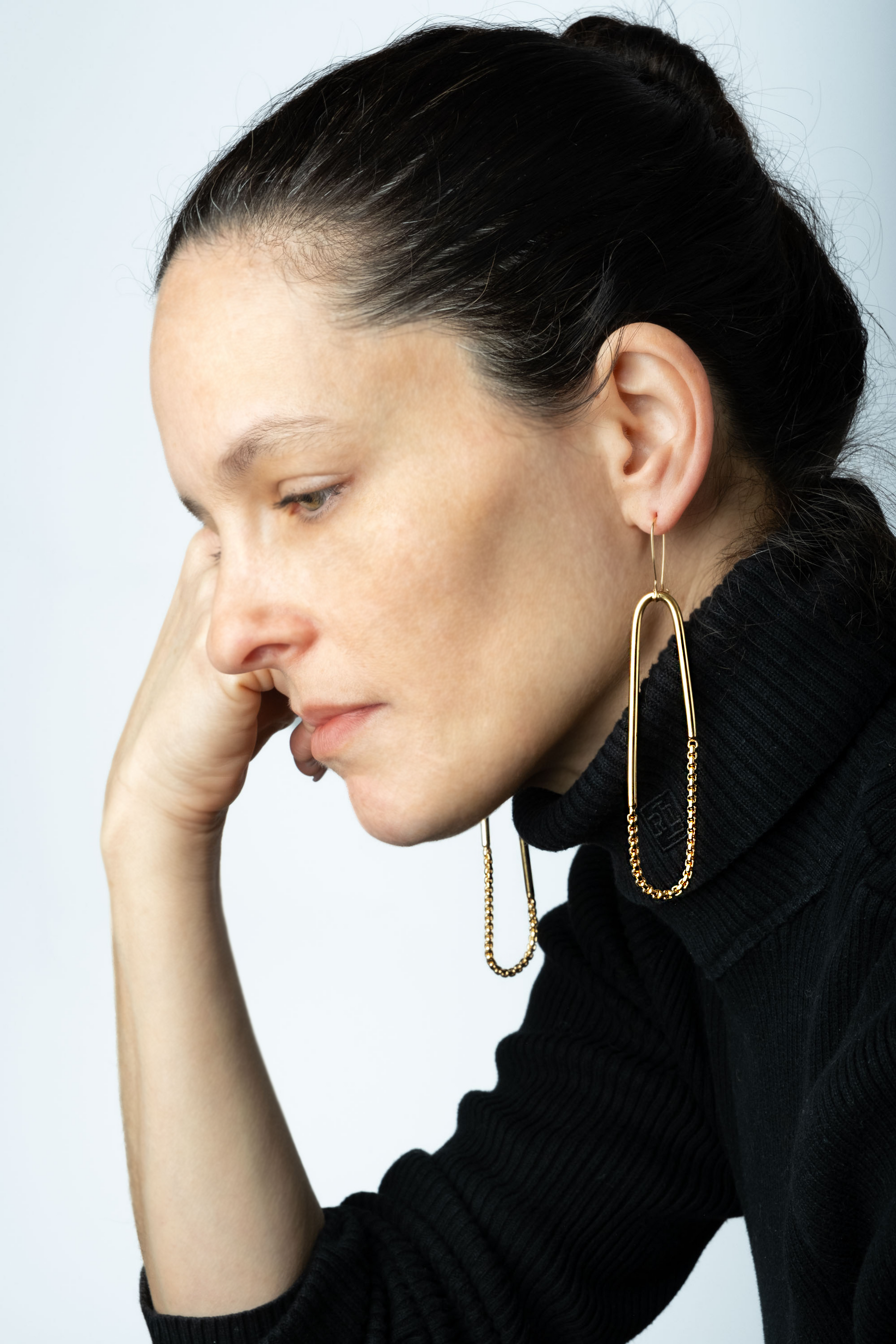 a woman with a black sweater and gold earrings