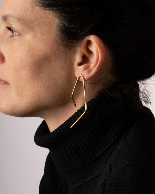 a woman wearing a black turtle neck sweater and gold hoop earrings