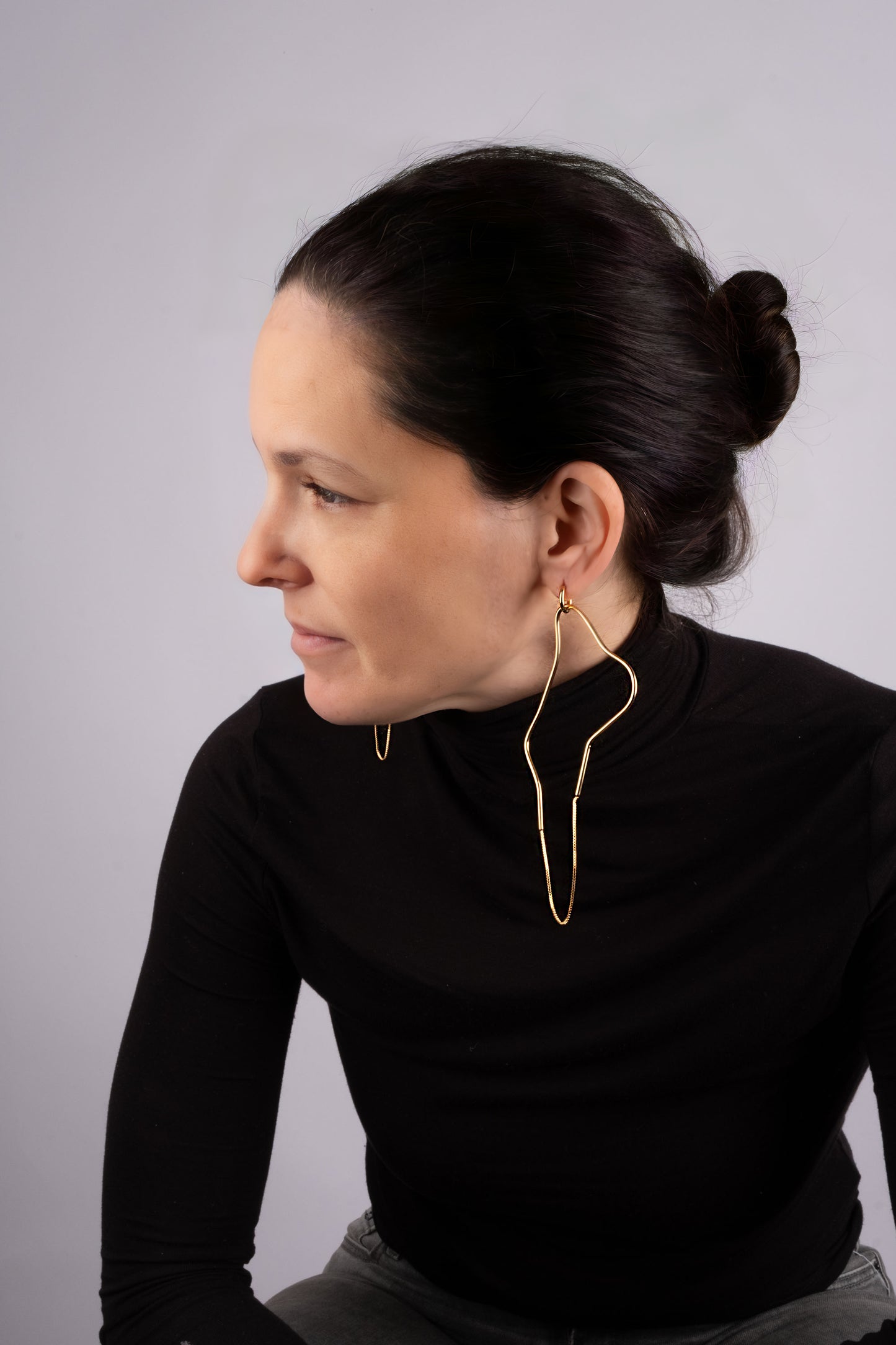 a woman wearing a black shirt and a pair of earrings