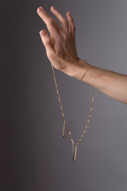 a woman's hand holding a gold necklace