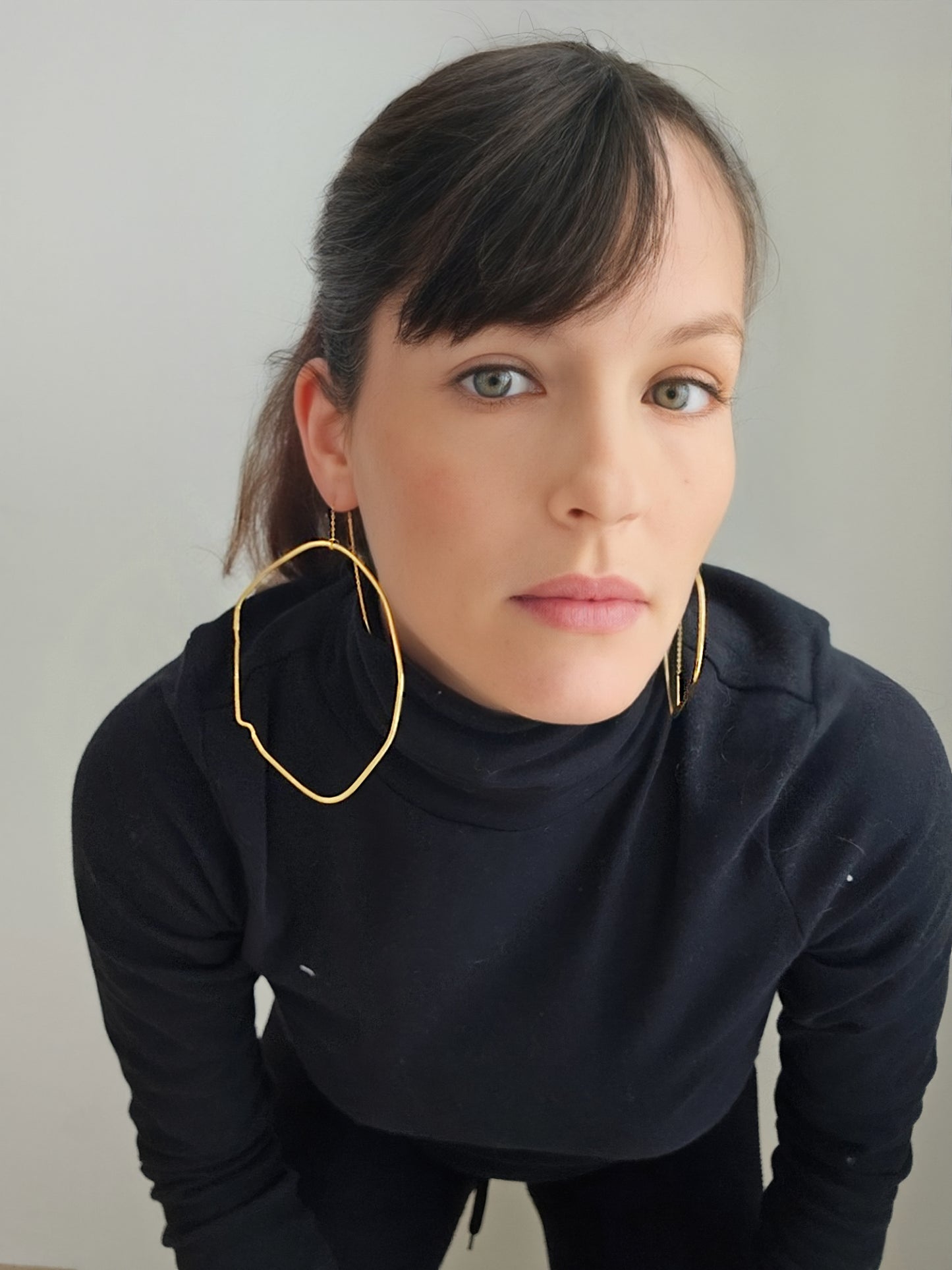 a woman wearing a black shirt and large gold hoop earrings