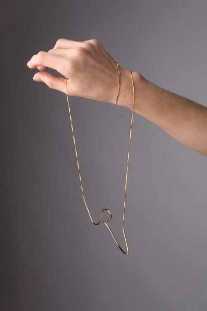 a woman's hand holding a gold necklace