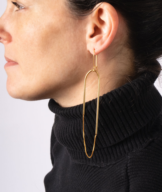 a woman wearing a black turtle neck sweater and large gold hoop earrings