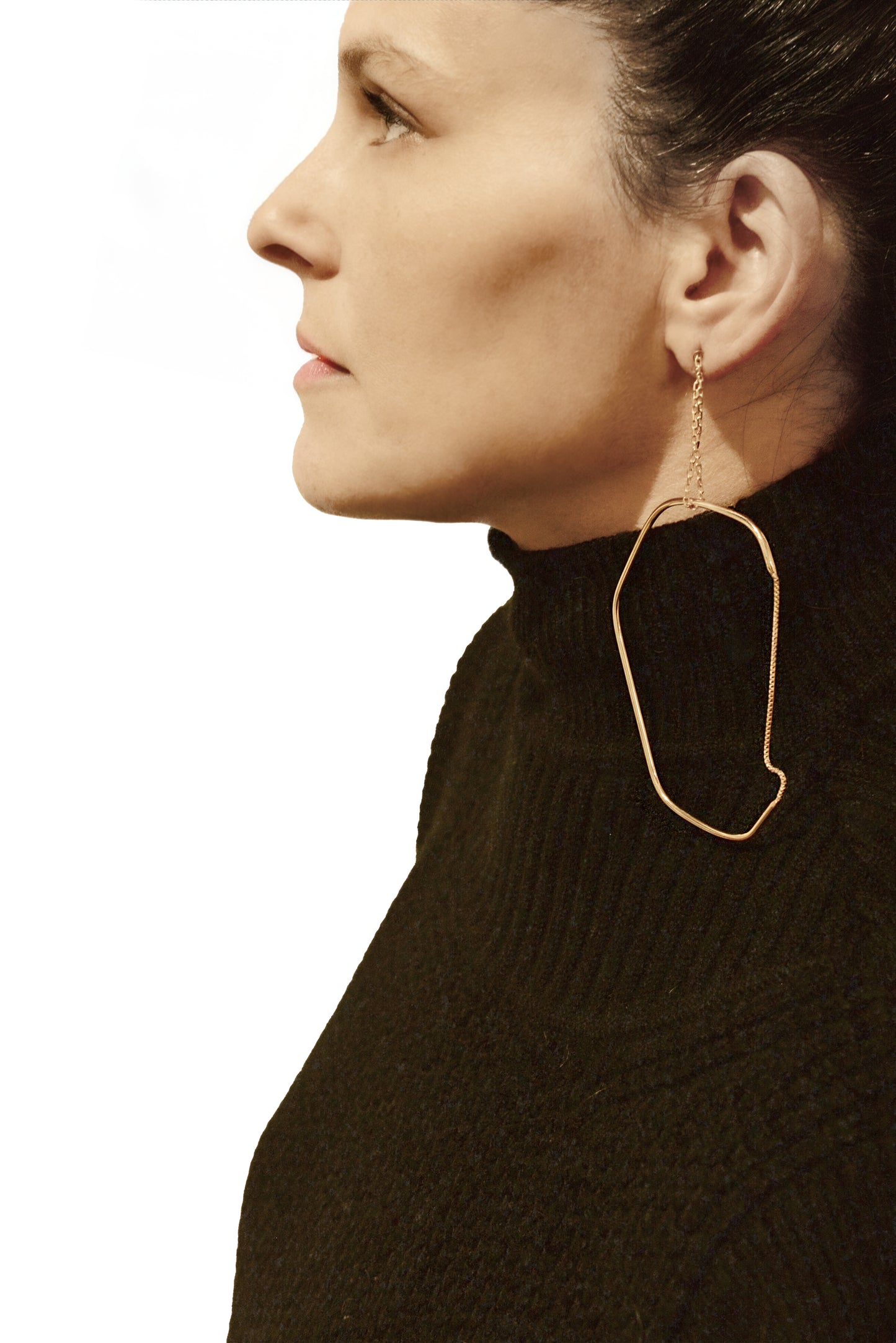 a woman wearing a black sweater and gold hoop earrings