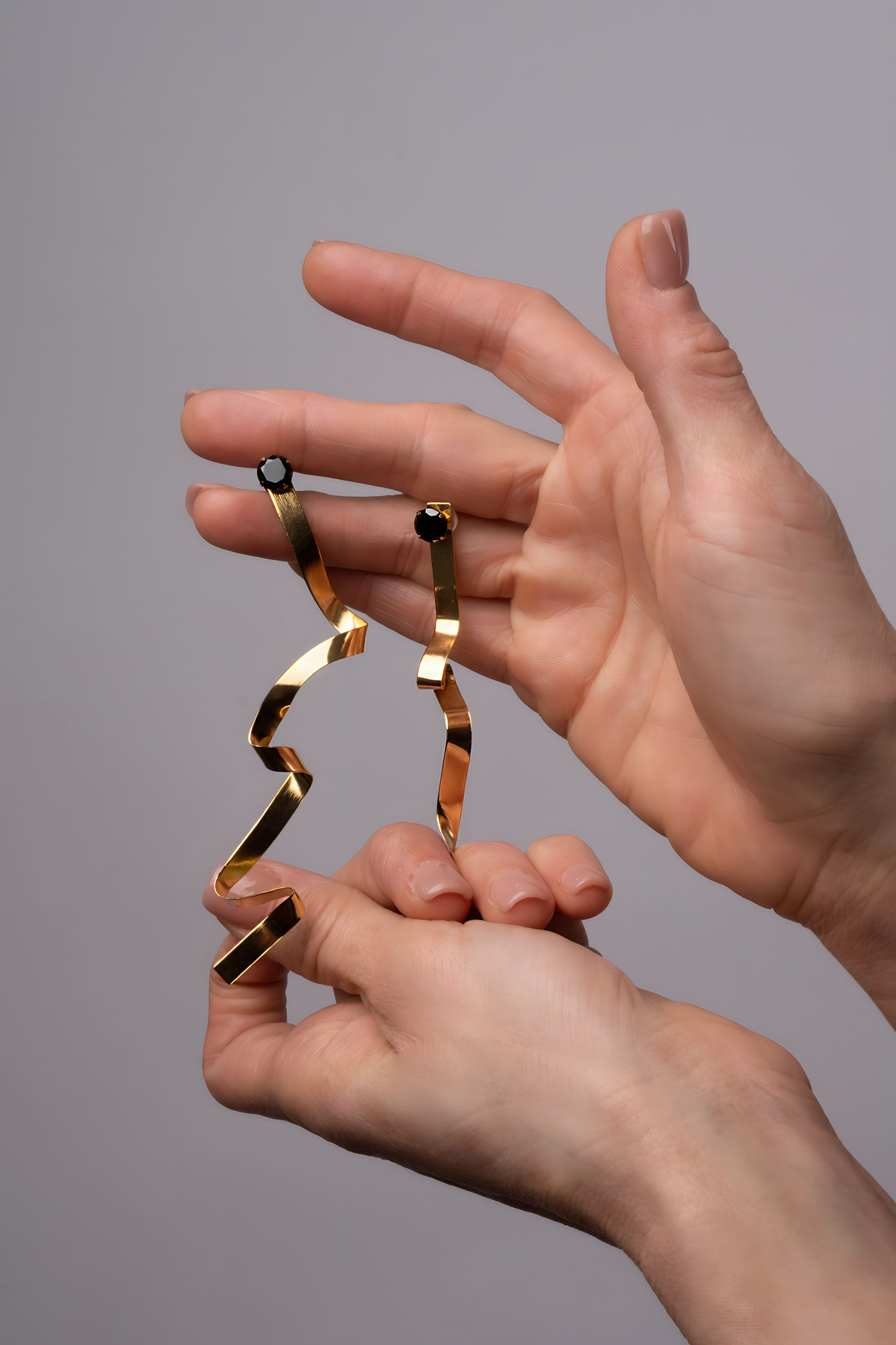 a pair of hands holding a pair of gold rings