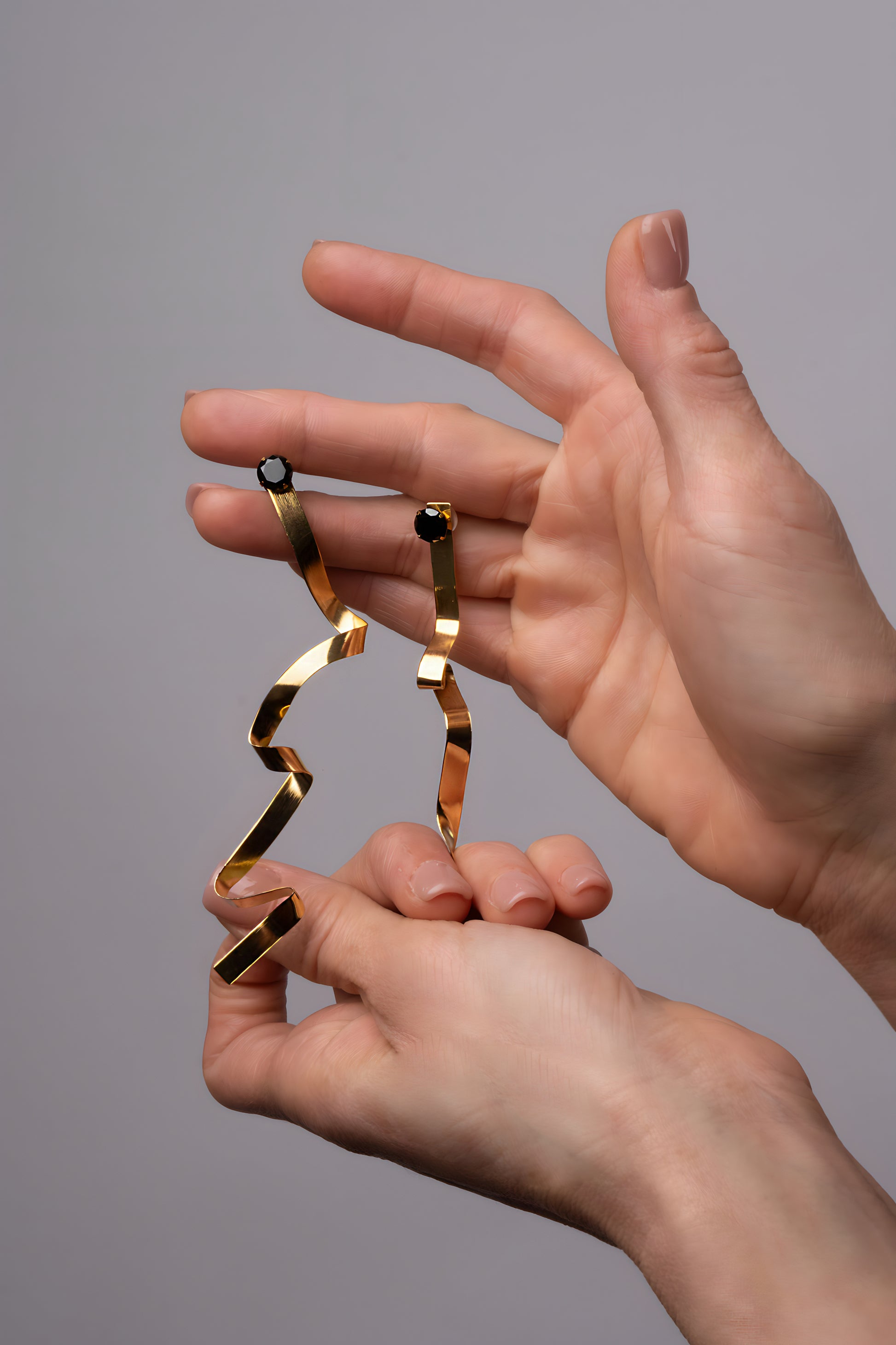 a pair of hands holding a pair of gold rings