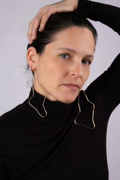 a woman wearing a black top and gold hoop earrings