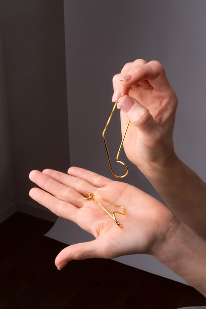 a person holding a pair of gold earrings
