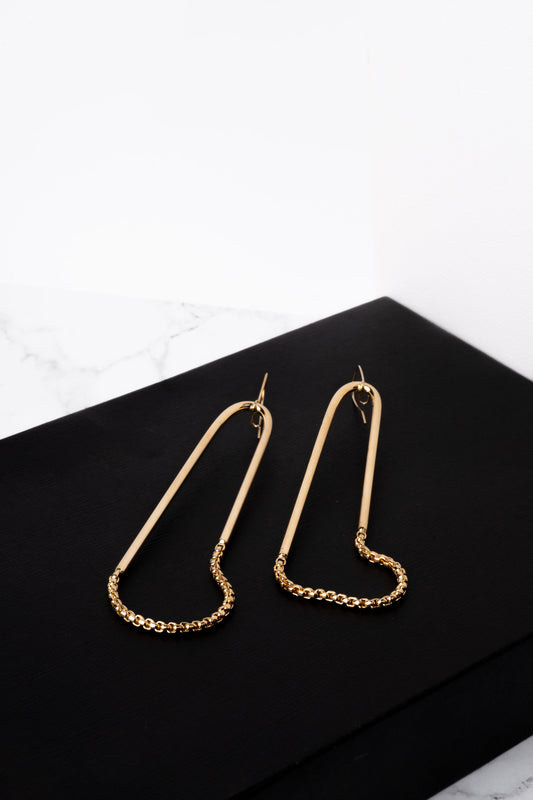 a pair of gold earrings on a black surface