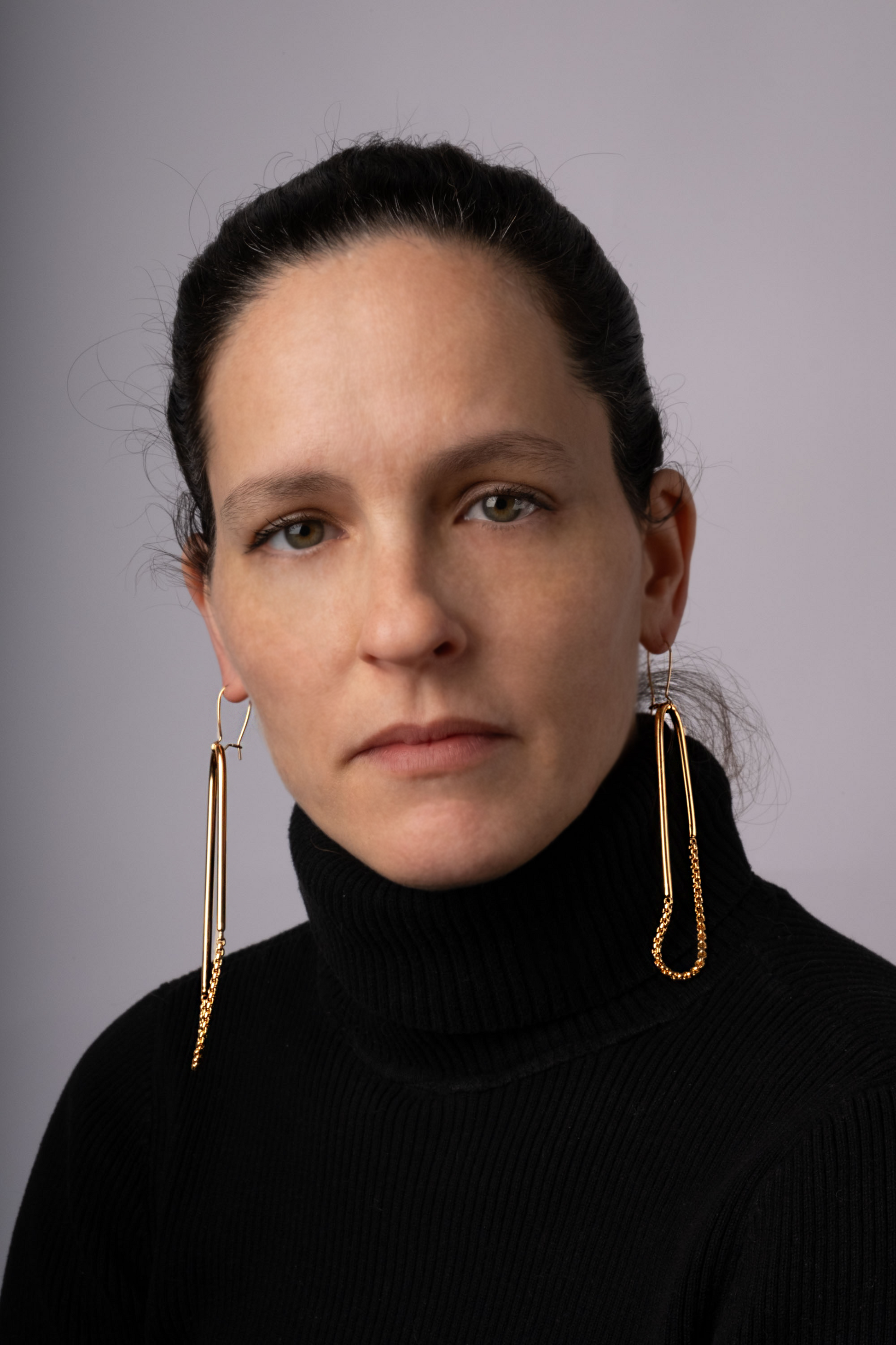 a woman wearing a black turtle neck sweater and gold earrings