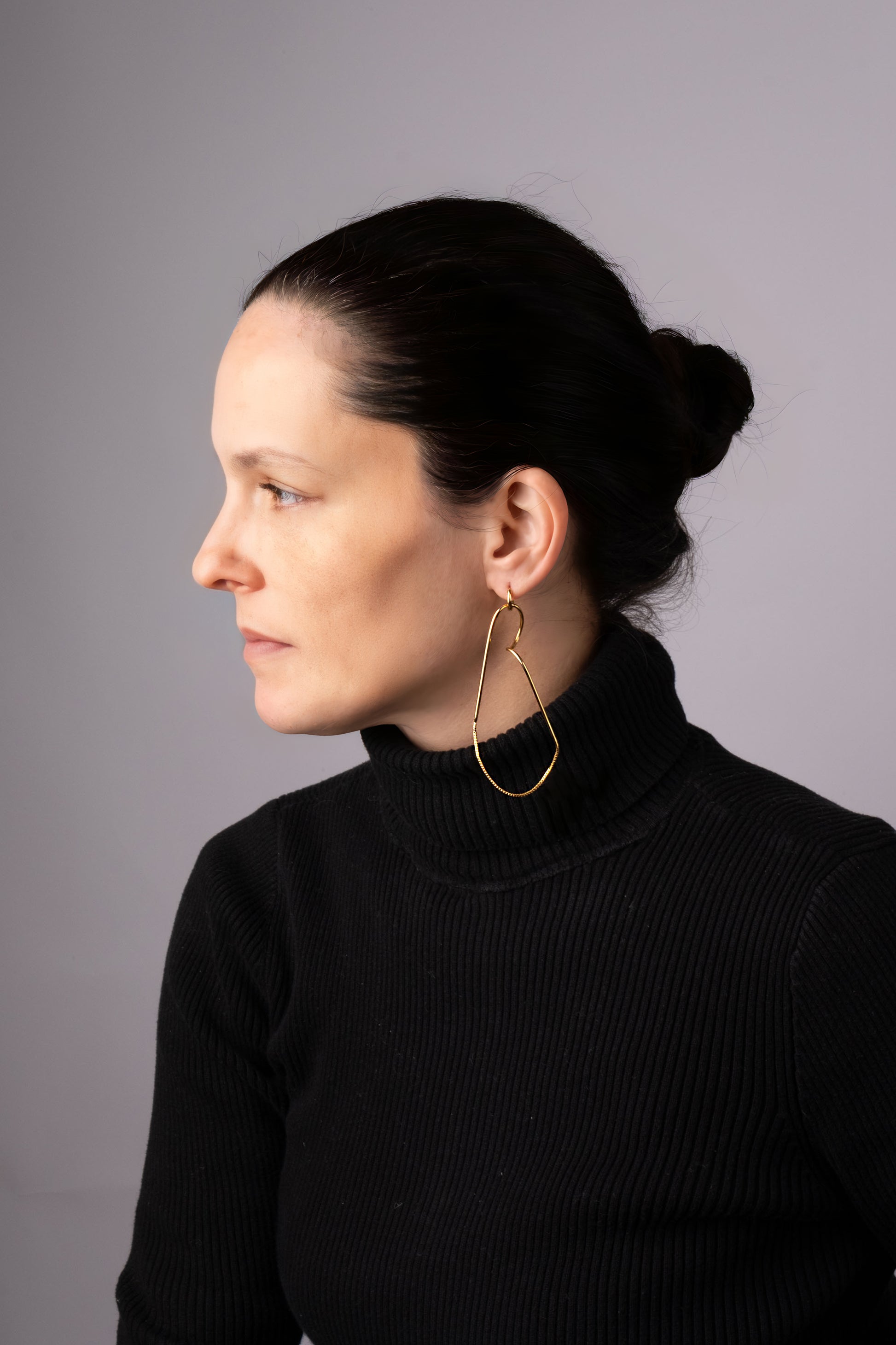 a woman wearing a black sweater and gold hoop earrings