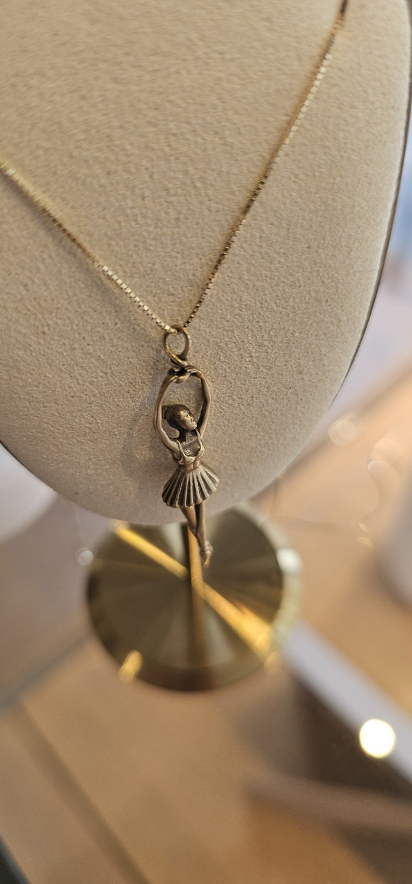 Ballerina Pendant in 14k gold on a box chain, on a display bust in the OTILYAS studio