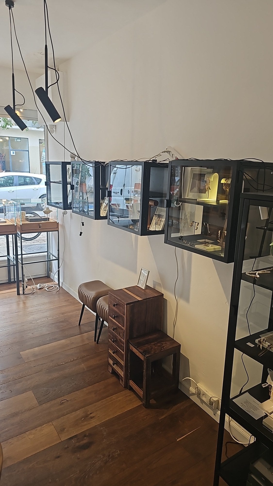 Black display cases, leather stools and a wooden drawer cabinet in the OTILYAS studio