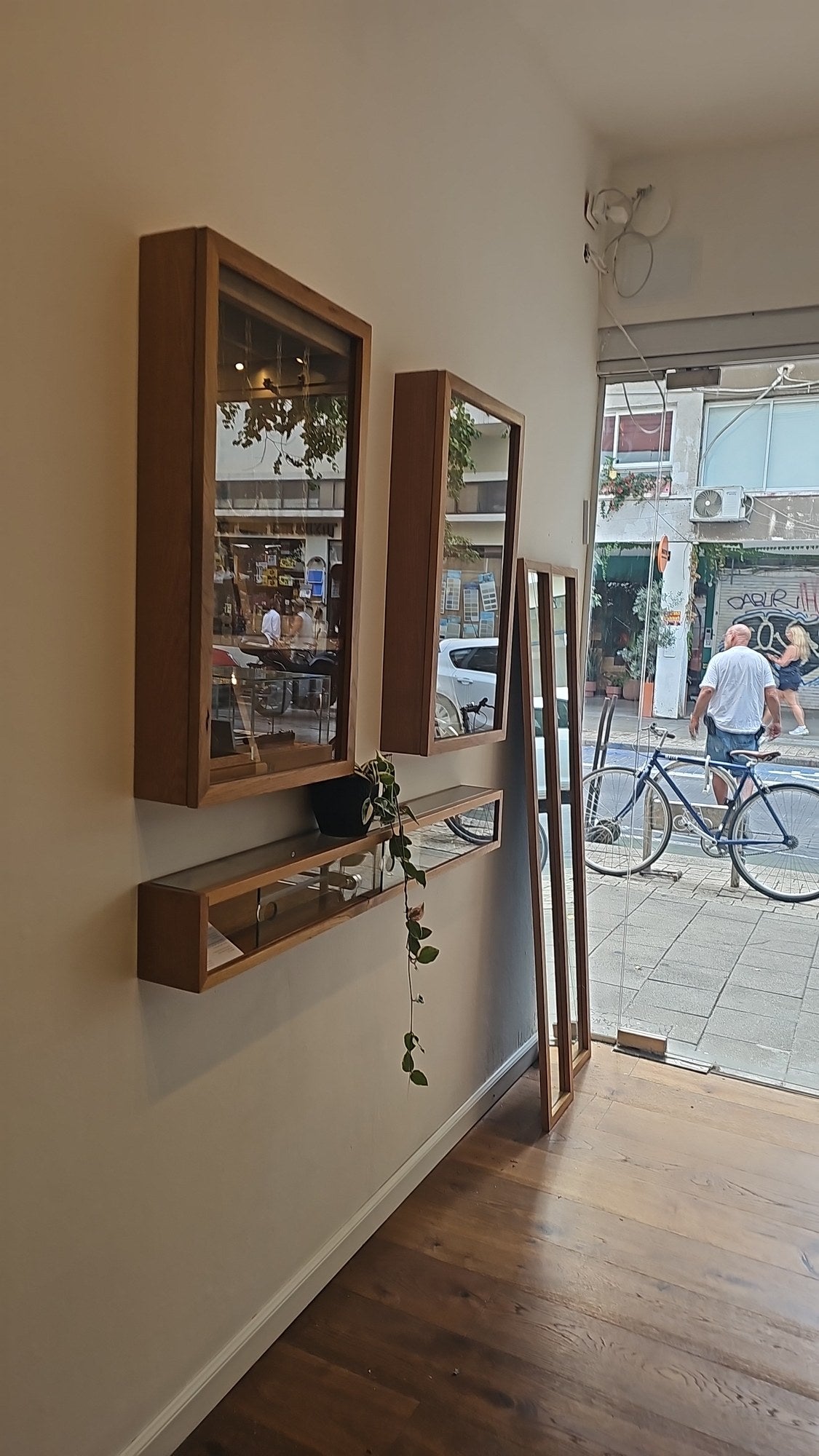 Oak framed mirrors and a display shelf by the street window of the OTILYAS studio