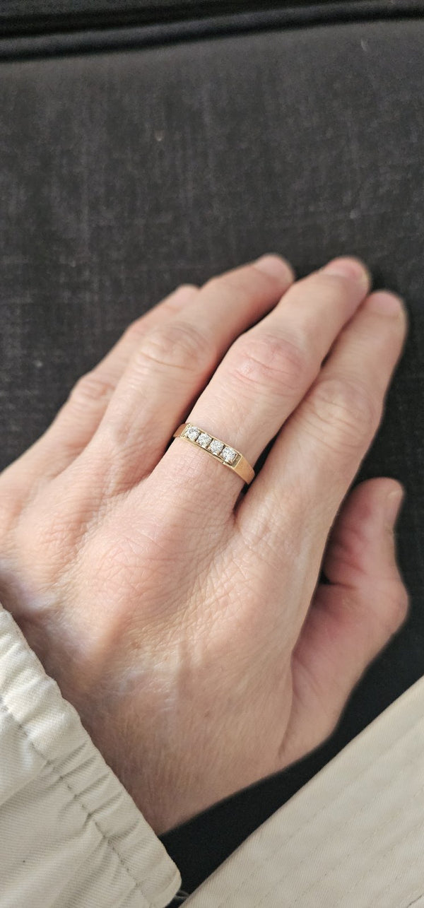 The Quartet Ring worn on the hand, four diamonds in a row on a yellow gold band