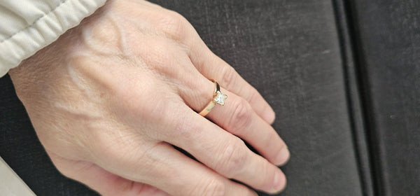 The Sun Square Ring worn on the finger, yellow gold band with a princess-cut diamond