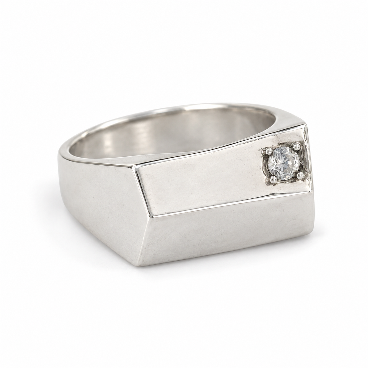 Side view of the silver pinky signet ring, showing the zircon set near one edge of the flat top