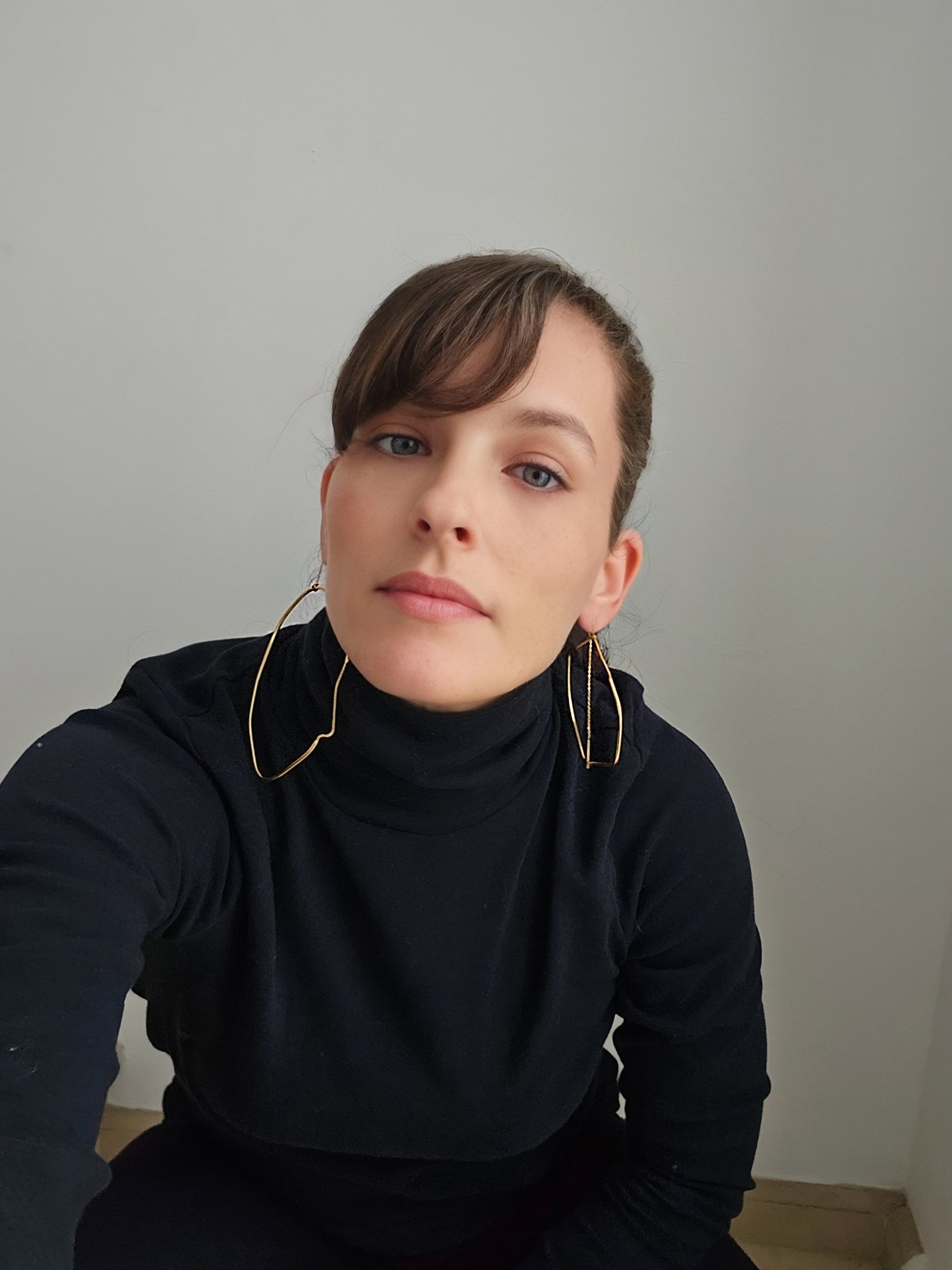 a woman wearing a black shirt and gold hoop earrings