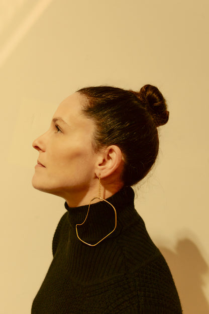 a woman wearing a black sweater and gold earrings